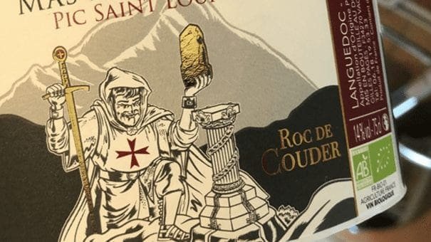 Wine label features medieval knight, sword, gold object, and details on Pic Saint Loup, Languedoc.