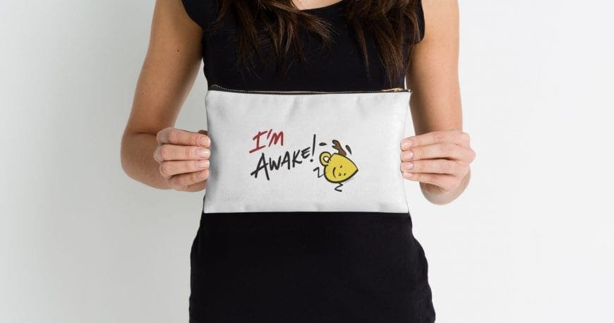 Person holding a pouch with a cartoon coffee cup and "I'm Awake!" text.