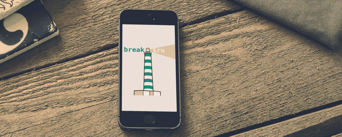 Smartphone on wood surface showing lighthouse with "breaksru" text.