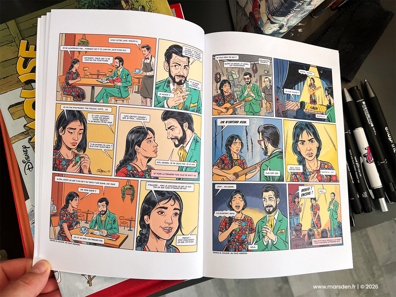 Printed bande dessinée spread from Samara with café scenes and a live musical performance, illustrated by Ian David Marsden.