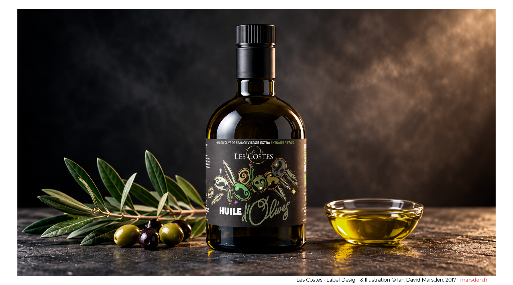 Dark glass olive oil bottle featuring original illustrated label design by Ian David Marsden, photographed with olive branches and a bowl of golden olive oil.