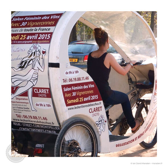 Vue rapprochée du côté d’un vélo-taxi avec le logo illustré Les Héritières de Bacchus et les informations du salon 2015 imprimées sur la carrosserie.